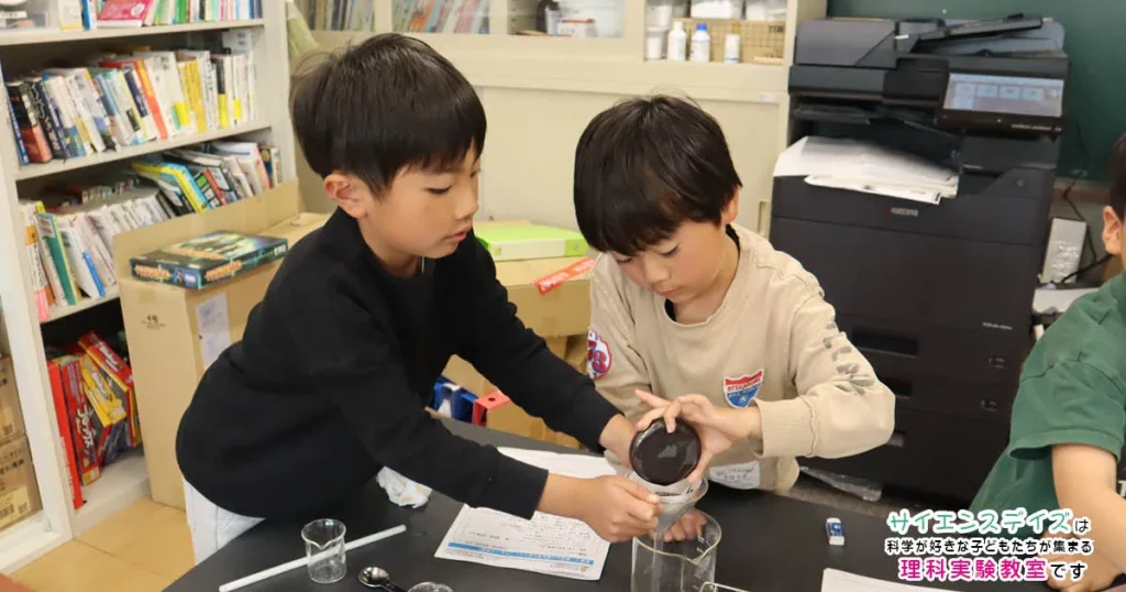 実験で協力して作業を進める小学生低学年の男の子2人 - チームワークを学びながら実験を進めるサイエンスデイズの授業