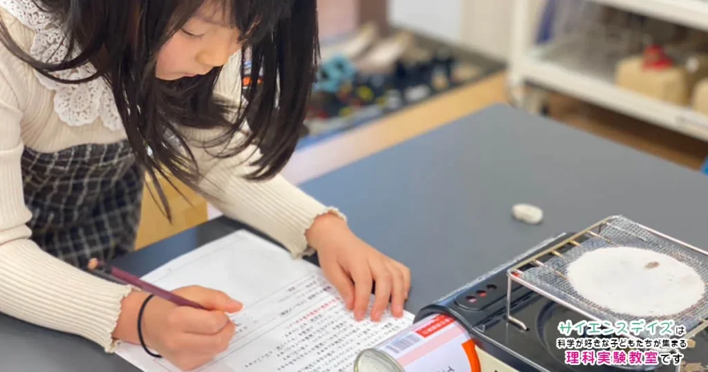 実験結果を観察・記録している小学生低学年の女の子 - 観察力と表現力を育むサイエンスデイズの授業風景