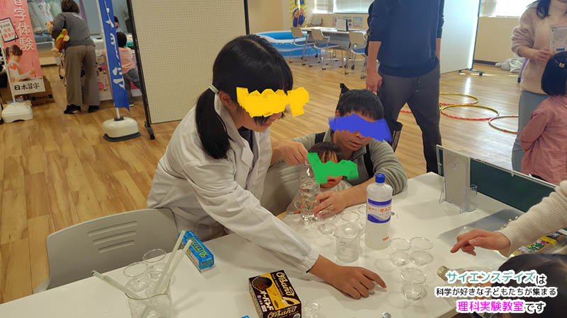 スライム作りの手順を笑顔で分かりやすく解説する小学生の女の子 - 成功体験を通じて自信を深めるサイエンスデイズの理科実験授業