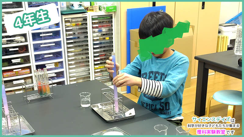 温度の違う水が入った試験管を慎重に重ねて観察する小学生 - サイエンスデイズの密度実験