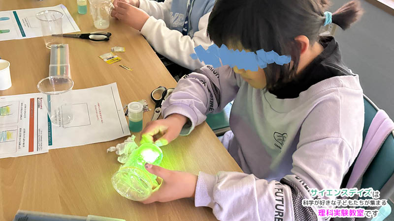 ブラックライトで光るスライムを見つめる女の子 - サイエンスデイズの出張理科実験ワークショップ