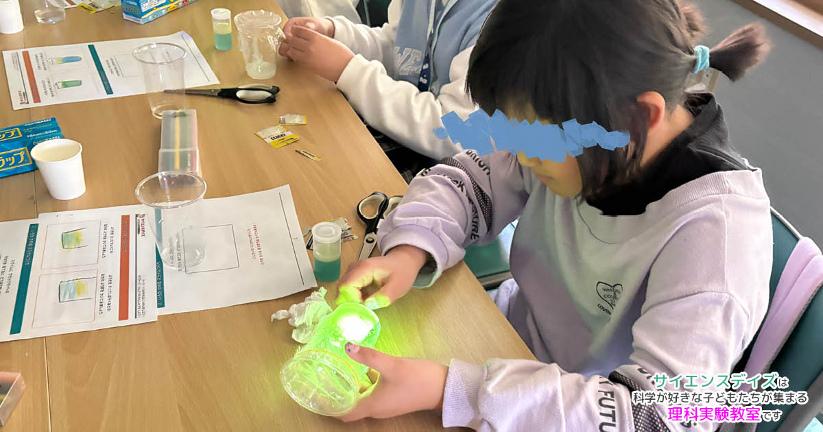 ブラックライトで光るスライムを見つめる女の子 - サイエンスデイズの出張理科実験ワークショップ