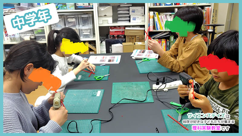 針金コイルの形を手で調整する小学中学年の子ども - サイエンスデイズの理科実験授業