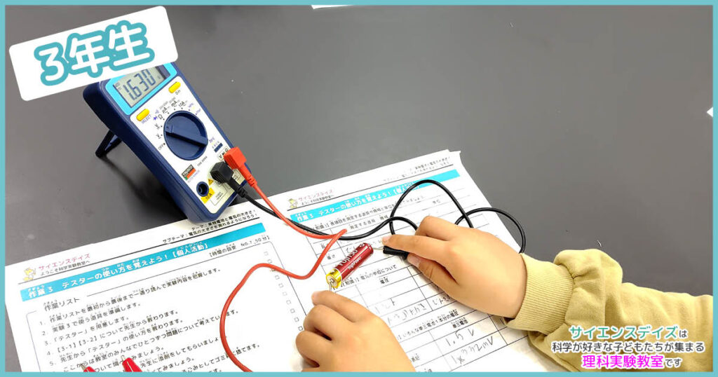 テスターで乾電池の電圧を測定する練習をする小学3年生 - 測定器の使い方を学ぶサイエンスデイズの理科実験