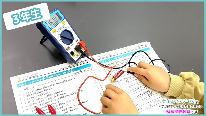 テスターで乾電池の電圧を測定する練習をする小学3年生 - 測定器の使い方を学ぶサイエンスデイズの理科実験