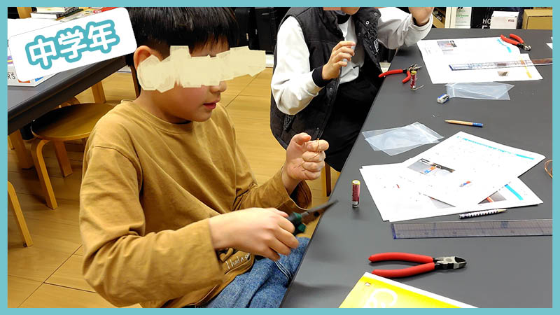 シンプルモーターの配線を確認しながら作業する小学中学年の子ども - サイエンスデイズの理科実験授業