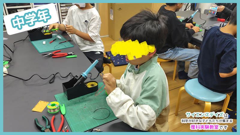 はんだごてを手に持ち作業する中学年の子ども - 本物の工具で電気工作に挑戦するサイエンスデイズの体験型授業