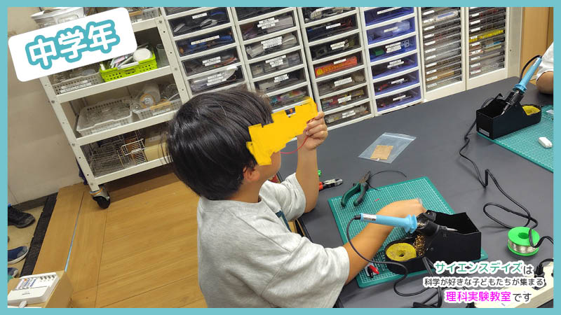 完成したみのむしクリップを手に取って確認する中学年の子ども - 電気回路を体験で学ぶサイエンスデイズの工作授業