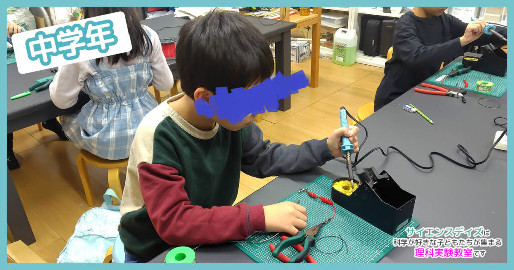 中学年の子どもがはんだごてでミノムシクリップを制作している様子