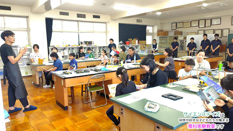 浜松聖星高等学校の理科室でアカミミガメ解剖実習の説明を聞く小学生と保護者