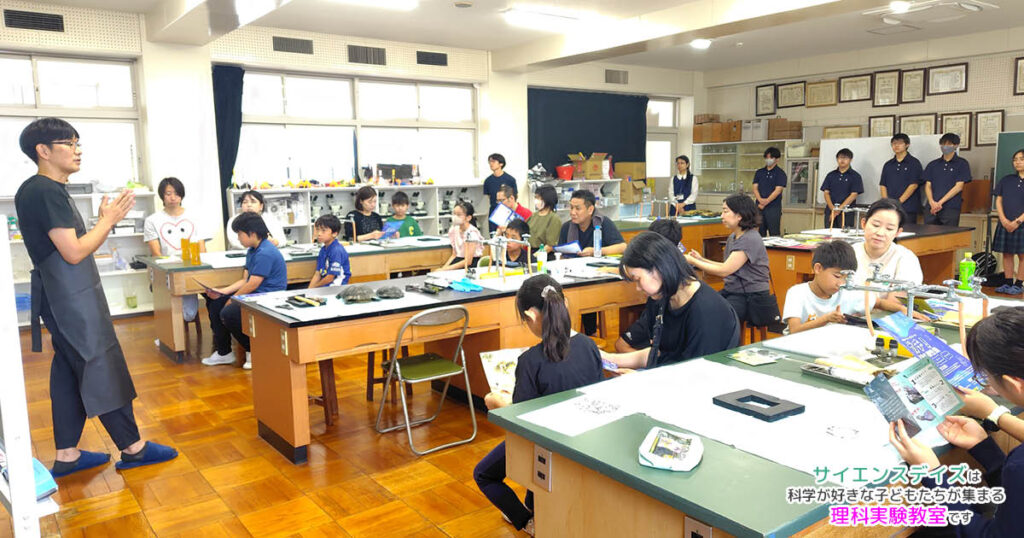 浜松聖星高等学校の理科室でアカミミガメ解剖実習の説明を聞く小学生と保護者