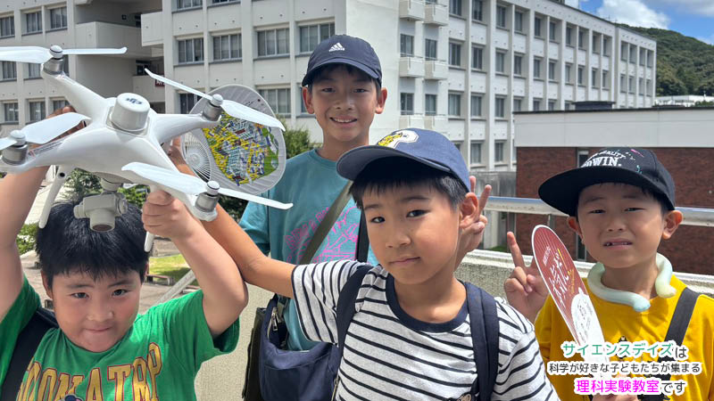 静岡理工科大学でのドローン体験で、ドローンを手に笑顔を見せる小学生たち