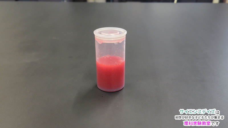 容器を約10回振った直後に赤色が強く混ざって見える水と油